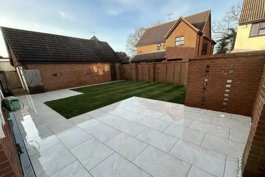 Large light porcelain patio with a new lawn and brick garden walls