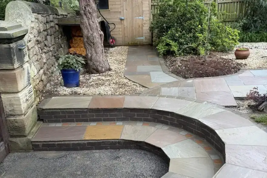 Curved Indian sandstone steps with brick risers leading to a garden shed