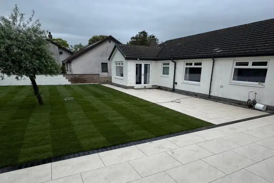 Large-format porcelain patio with charcoal sett border and freshly laid lawn — private residence, Dornoch