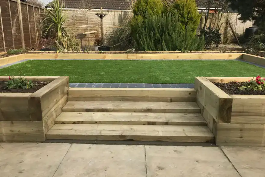 Wooden sleeper steps leading to a green lawn in a well-maintained backyard
