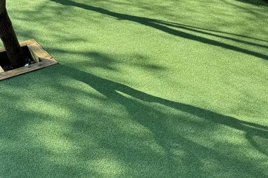 Artificial putting green close-up with golf hole cup and tree shadows