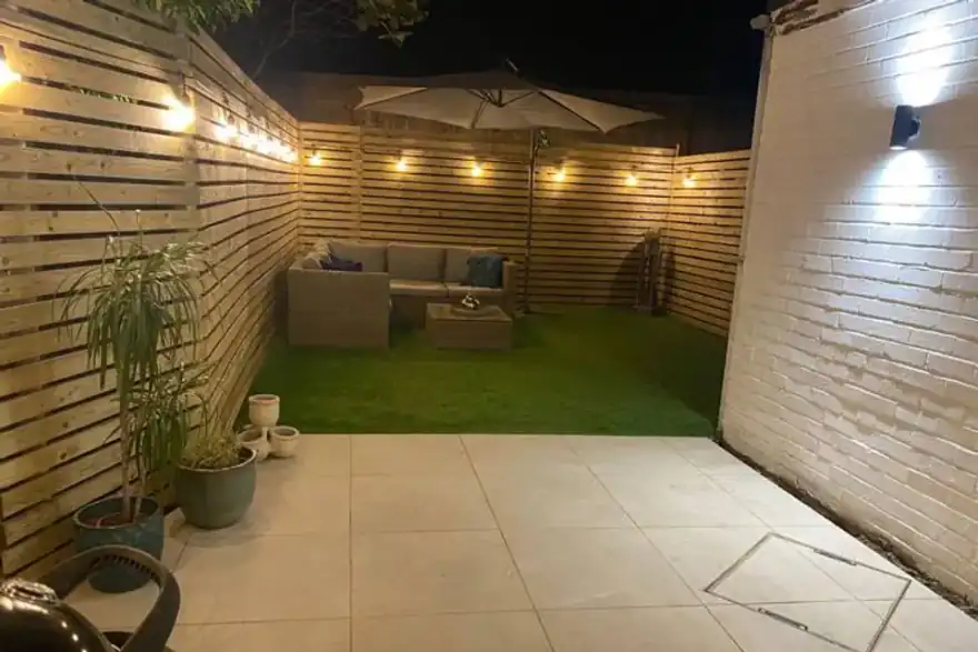 Night garden with patio, artificial grass and festoon lighting — completed garden project in Reading